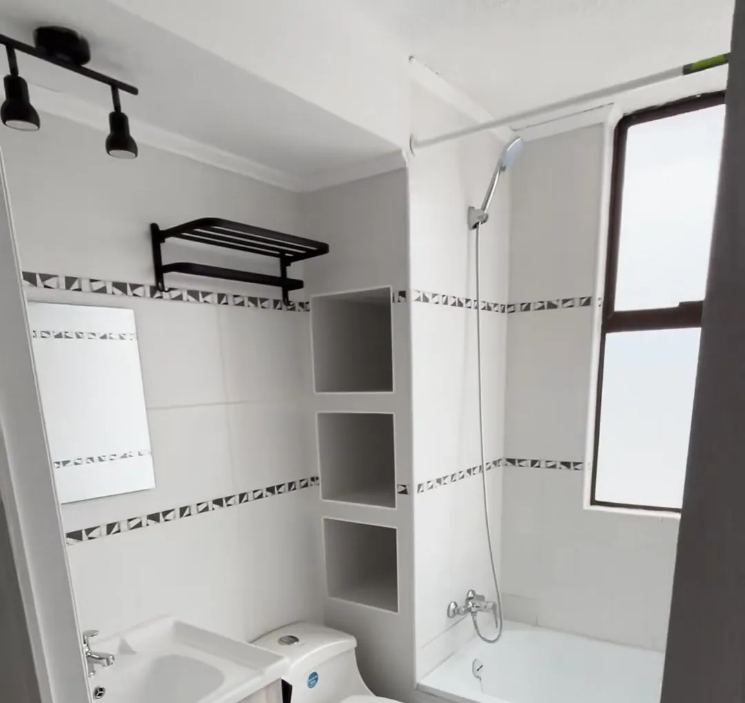 Baño terminado tras la remodelación, con muros claros y repisas nuevas