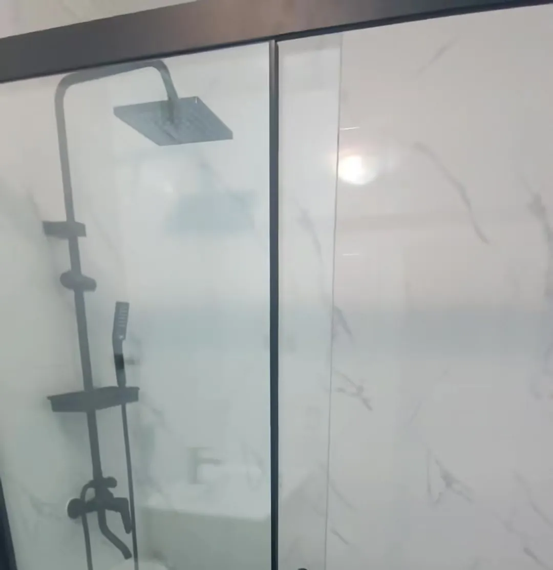 Baño remodelado con porcelanato tipo mármol, mampara y grifería negra